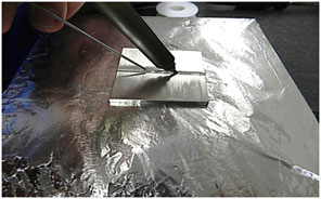 aluminum plates being joined via ultrasonic soldering with S-Bond solder wire fed to U/S soldering iron tip.