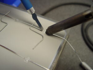 Ultrasonic soldering of tabbing wire to back panel of aluminized solar panel